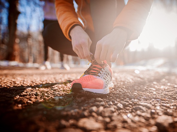 person running outdoors stopping to tie shoe laces